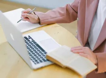 old hand on laptop and book